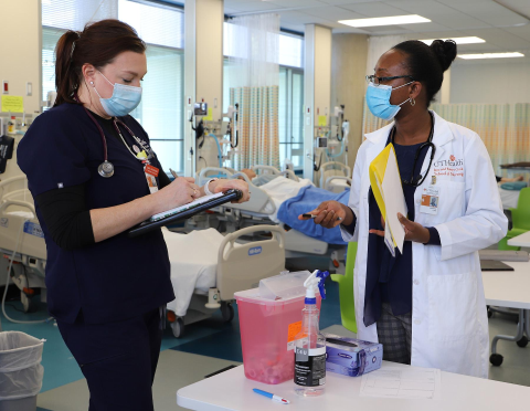 BSN student Sara Atkinson and FNP student Gersonie Luma discuss a “patient” during the intraprofessional simulation.
